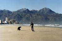 The Strand beachfront with surfers and snow on Kogelberg